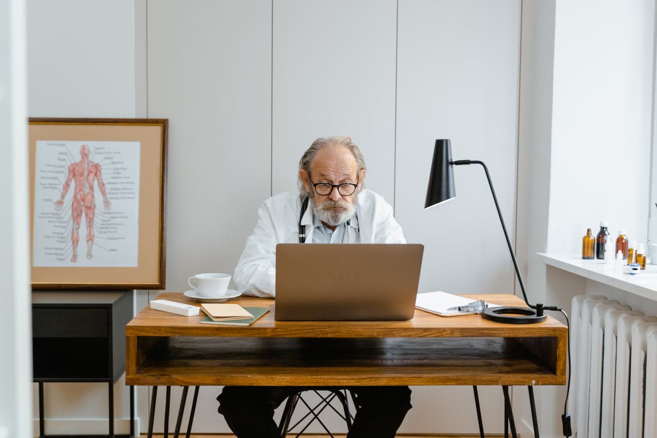 doctor in his clinic sitting on his desk with laptops.
